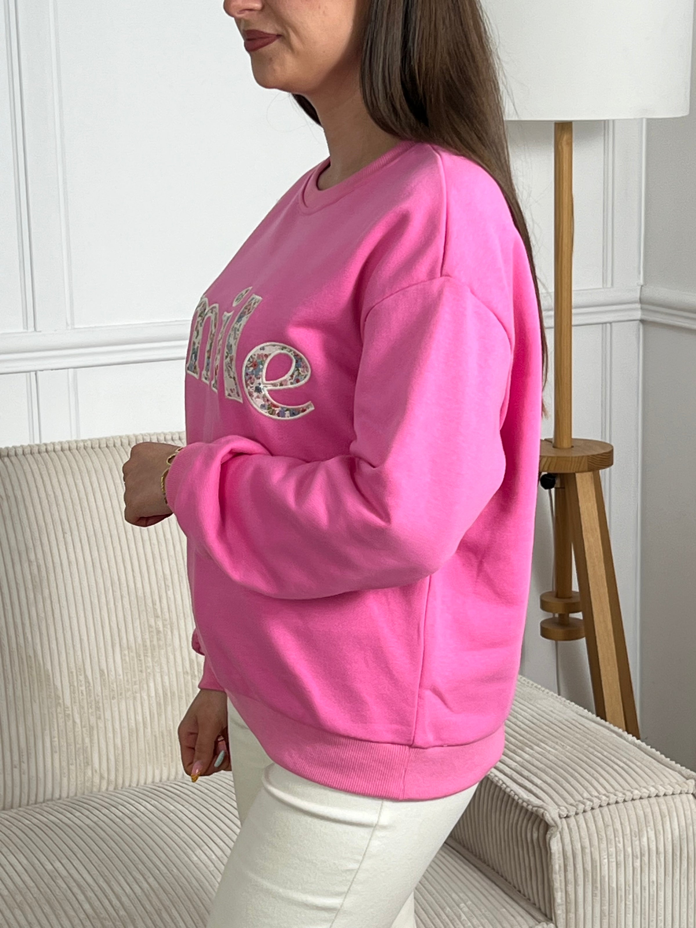 Sweat rose confortable aux manches longues, parfait pour les journées fraîches. Son col rond classique offre une allure intemporelle, tandis que l'inscription "SMILE" brodée avec des motifs fleuris délicats ajoute une touche de personnalité et de douceur. Un basique polyvalent à porter seul ou en superposition, idéal pour exprimer votre style avec bienveillance.