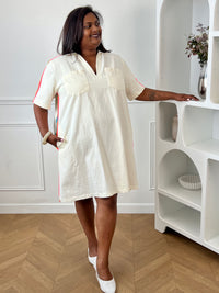 Adoptez un look estival plein de fraîcheur avec cette robe courte beige grande taille femme. Sa coupe ample assure un confort optimal au quotidien, tandis que son col chemise avec encolure en V apporte une touche d'élégance décontractée. Pratique et tendance, elle est dotée de deux poches poitrine et de deux poches latérales. Les rayures colorées sur les épaules et les côtés de la robe, dans des tons rose fluo, orange, jaune, bleu et vert.