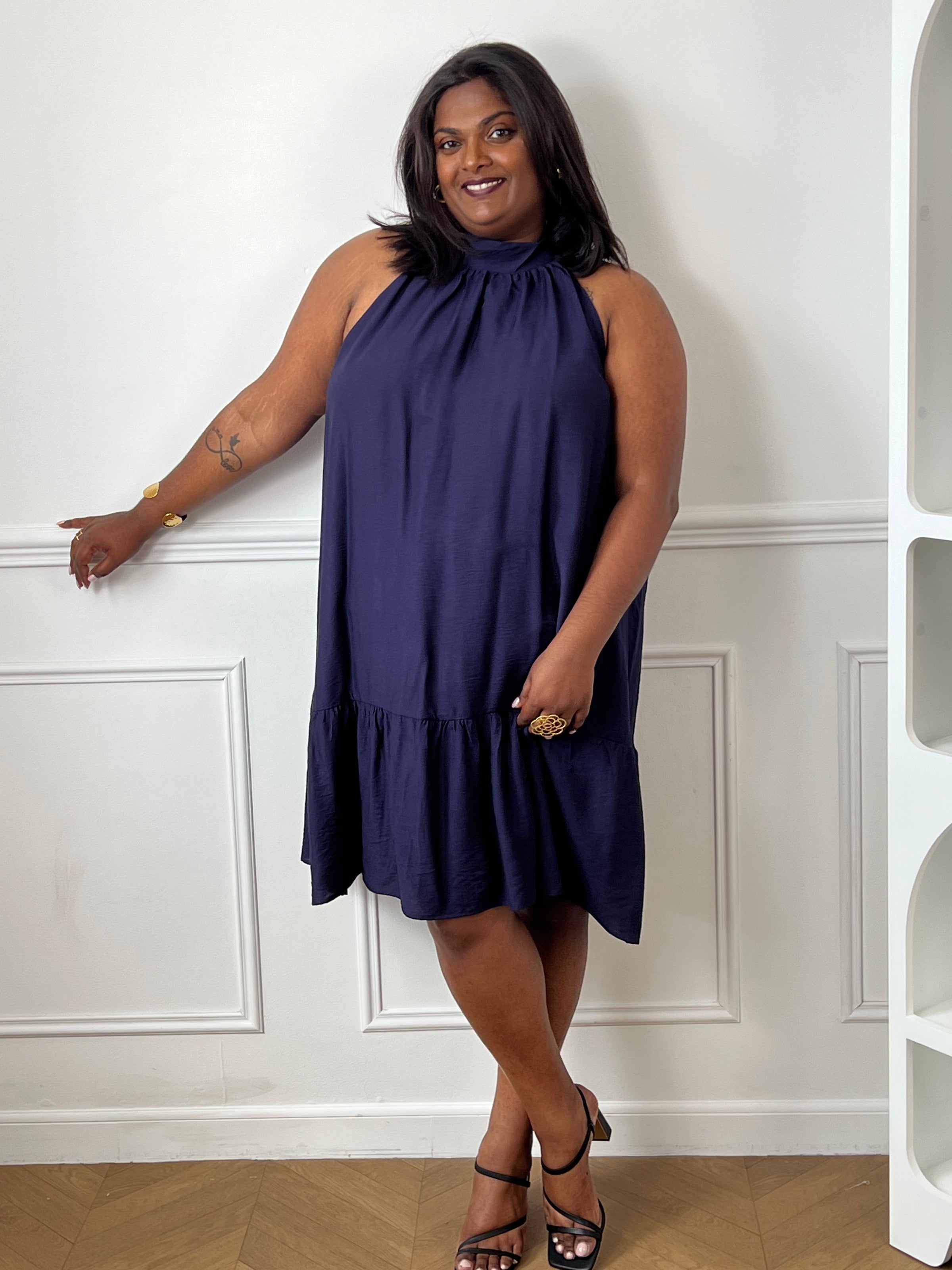 Élégante et aérienne, cette robe bleu marine grande taille est parfaite pour créer un look féminin et raffiné. Son col montant à nouer, son dos nu et sa coupe évasée lui confèrent une allure chic tout en restant agréable à porter. Sa matière légèrement transparente apporte une touche de légèreté idéale pour la belle saison.