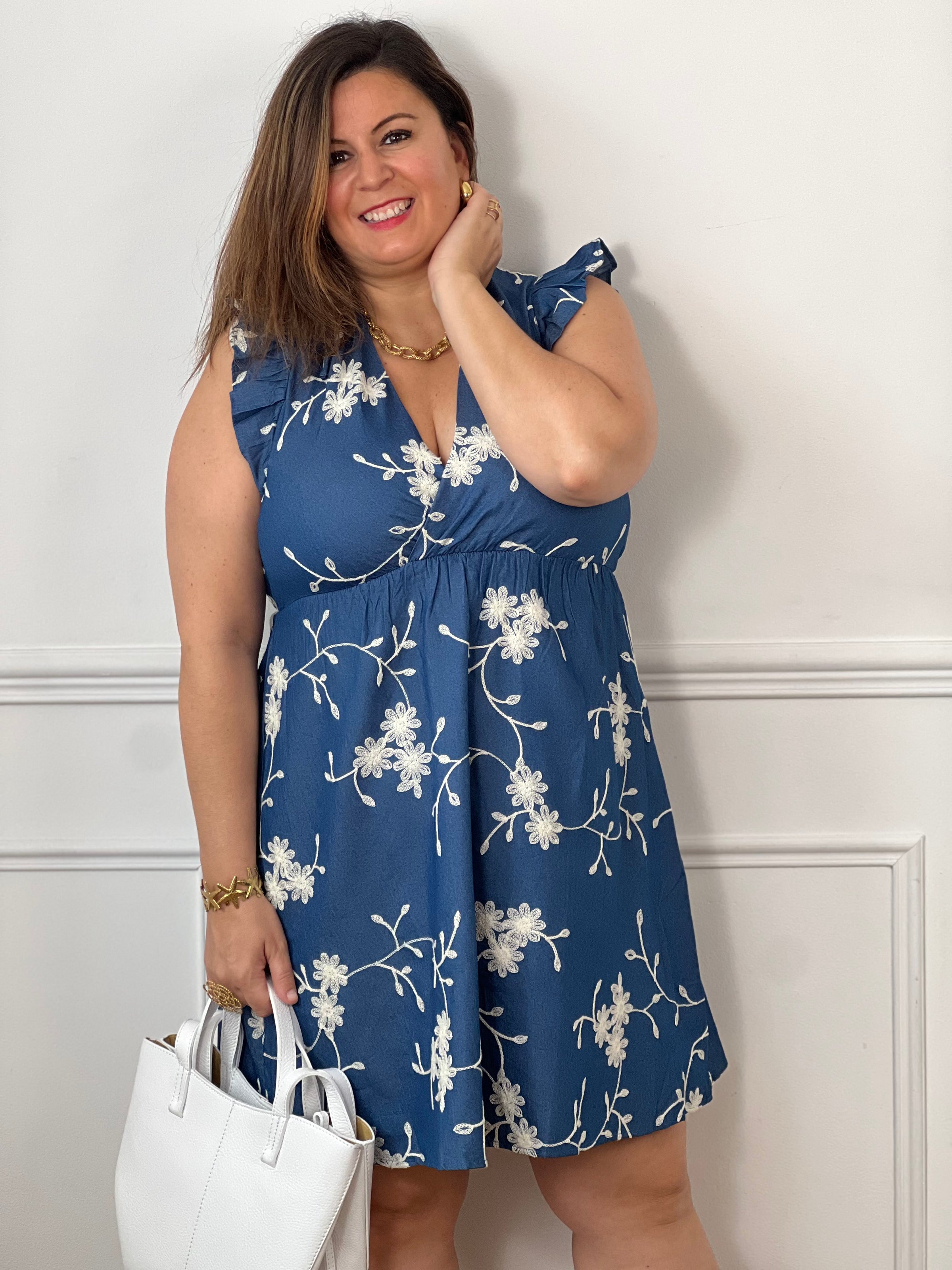Craquez pour cette robe en coton grande taille, ornée de délicates fleurs brodées bleu marine et écru. Son col cache-cœur devant et dos, ses volants aux épaules, sa taille élastiquée et son lien à nouer dans le dos offrent une coupe féminine et confortable. Doublée, elle est parfaite pour la belle saison.