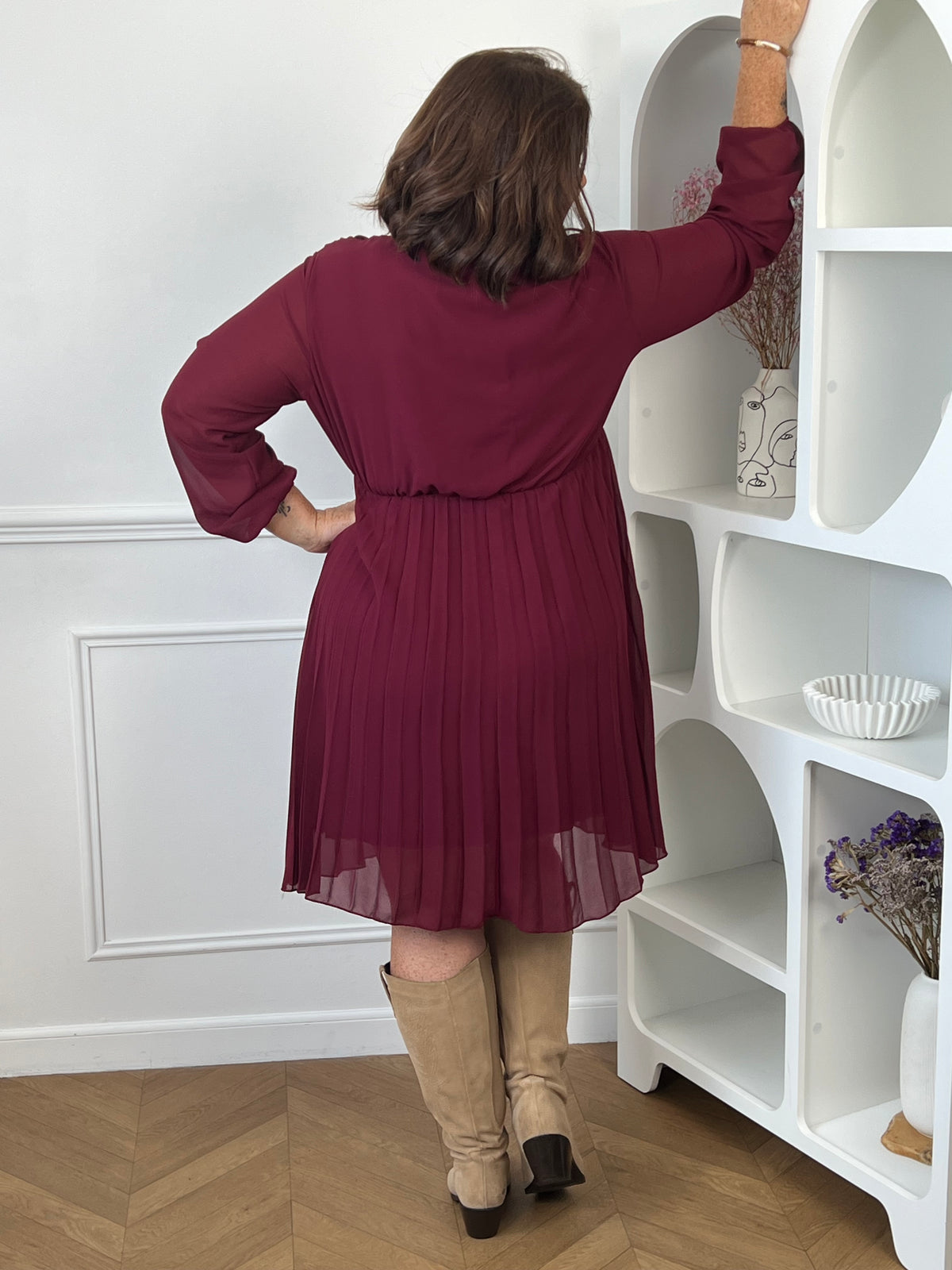 Robe courte bordeaux Ophelie portée de dos, montrant la taille marquée, les manches longues et la jupe plissée.