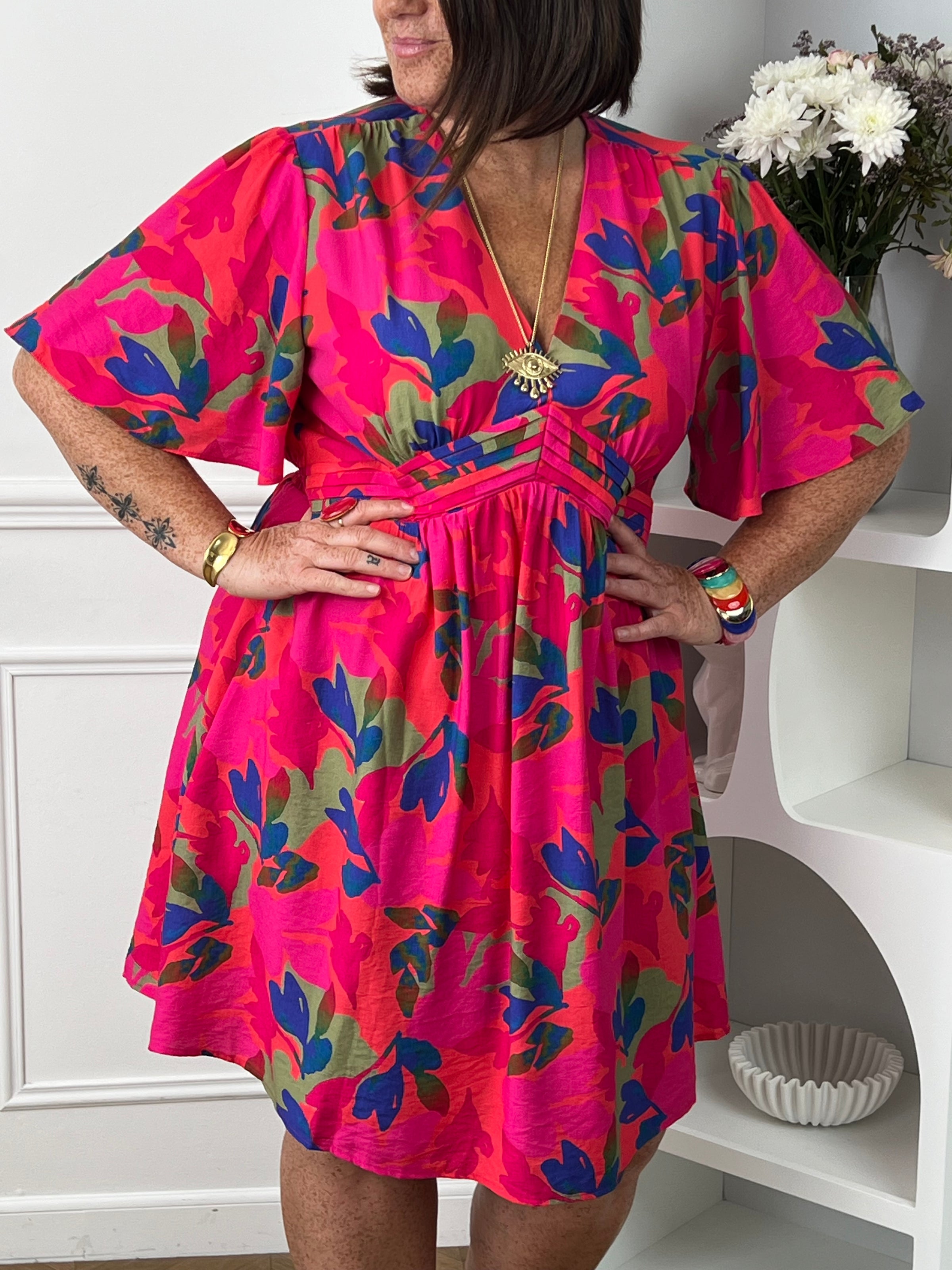 Cette robe courte fuchsia aux motifs corail bleu et vert allie confort et élégance grâce à sa coupe fluide qui sublime la silhouette. Son col en V et ses manches courtes apportent une touche de fraîcheur et de féminité.