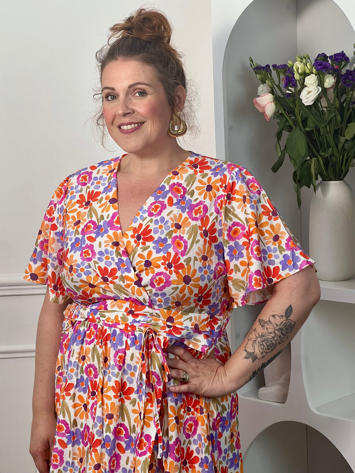 Robe courte grande taille femme, idéale pour une allure féminine et élégante. Dotée de manches courtes et d’un col cache-cœur, elle met en valeur la silhouette avec raffinement. Sa taille élastiquée au dos assure un confort optimal, tandis que les volants sur le bas apportent du mouvement et de la légèreté. Cette robe colorée aux tons orange, vert, violet, rose et écru est parfaite pour un look chic et tendance.