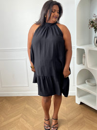 Sublimez votre silhouette avec cette robe noire grande taille au style élégant et féminin. Sa coupe évasée apporte fluidité et confort, tandis que son col montant avec lien à nouer ajoute une touche raffinée. Sans manches et dotée d’un dos nu séduisant, elle est idéale pour les journées ensoleillées comme pour les occasions spéciales. Légèrement transparente, cette robe noire allie légèreté et sophistication pour un look résolument chic.