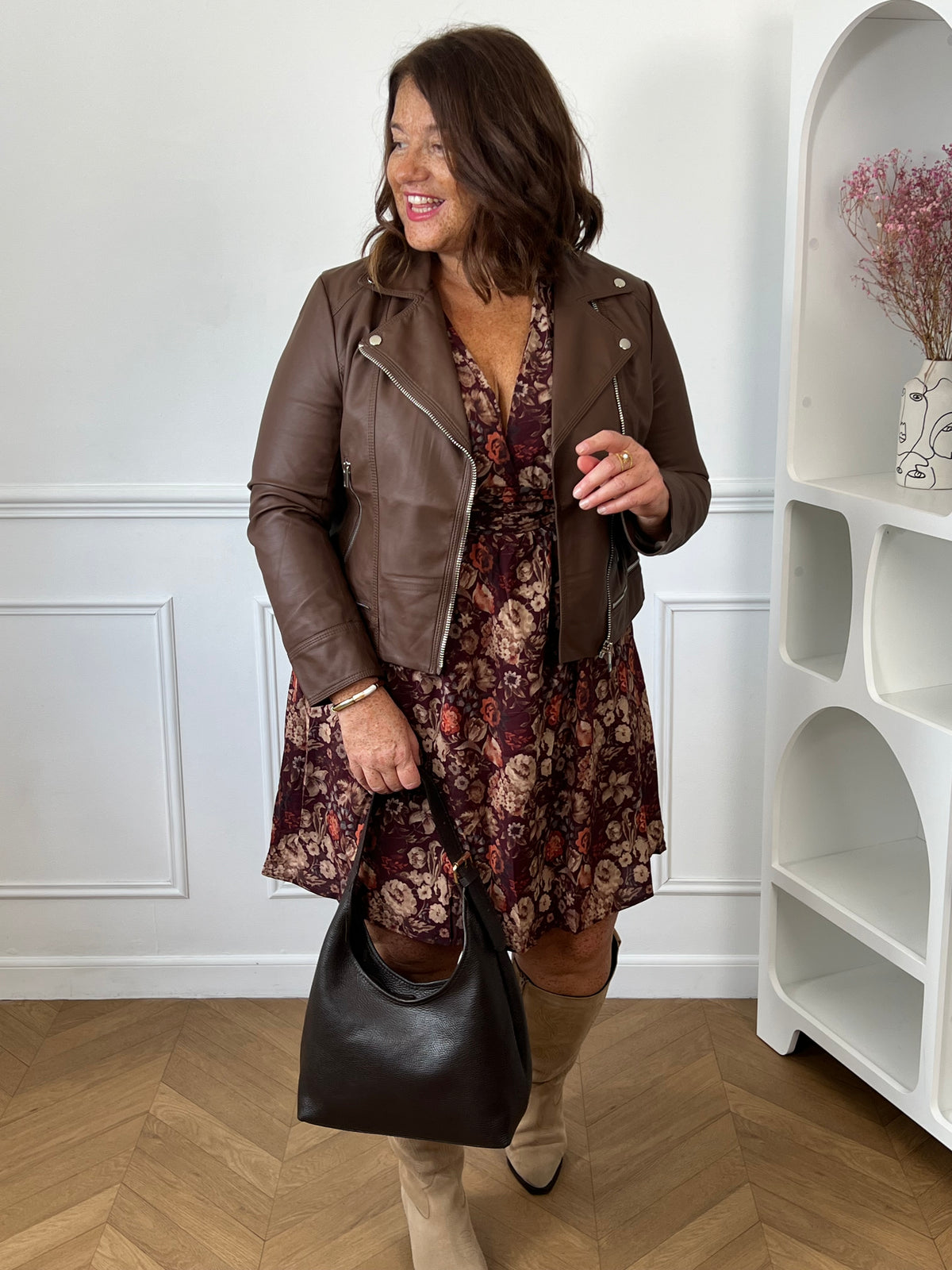 Robe bordeaux fleurie portée sous une veste marron avec des bottes beiges et un sac noir – Macy | Loïcia