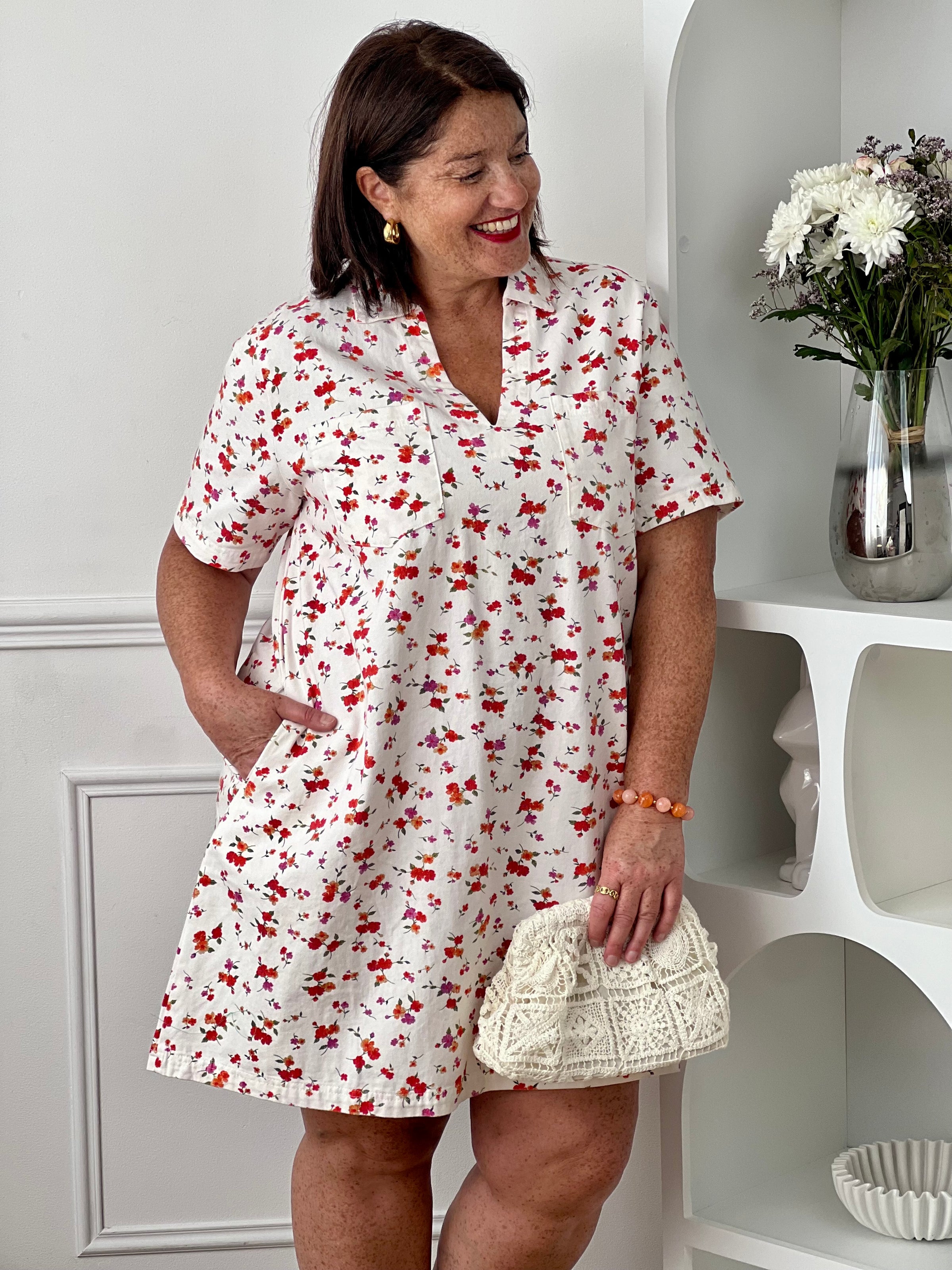 Robe à motifs femme grande taille, parfaite pour une allure féminine et colorée. Avec ses manches courtes, son col chemise ouvert en V et sa coupe ample, elle offre confort et élégance au quotidien. Dotée de deux poches poitrine et de deux poches latérales, elle allie style et praticité. Ses motifs fleuris aux tons écru, rouge, orange, vert et violet apportent une touche lumineuse et tendance, tandis que les boutons dorés aux poignets ajoutent une finition raffinée. Confectionnée en 100% coton, cette robe e
