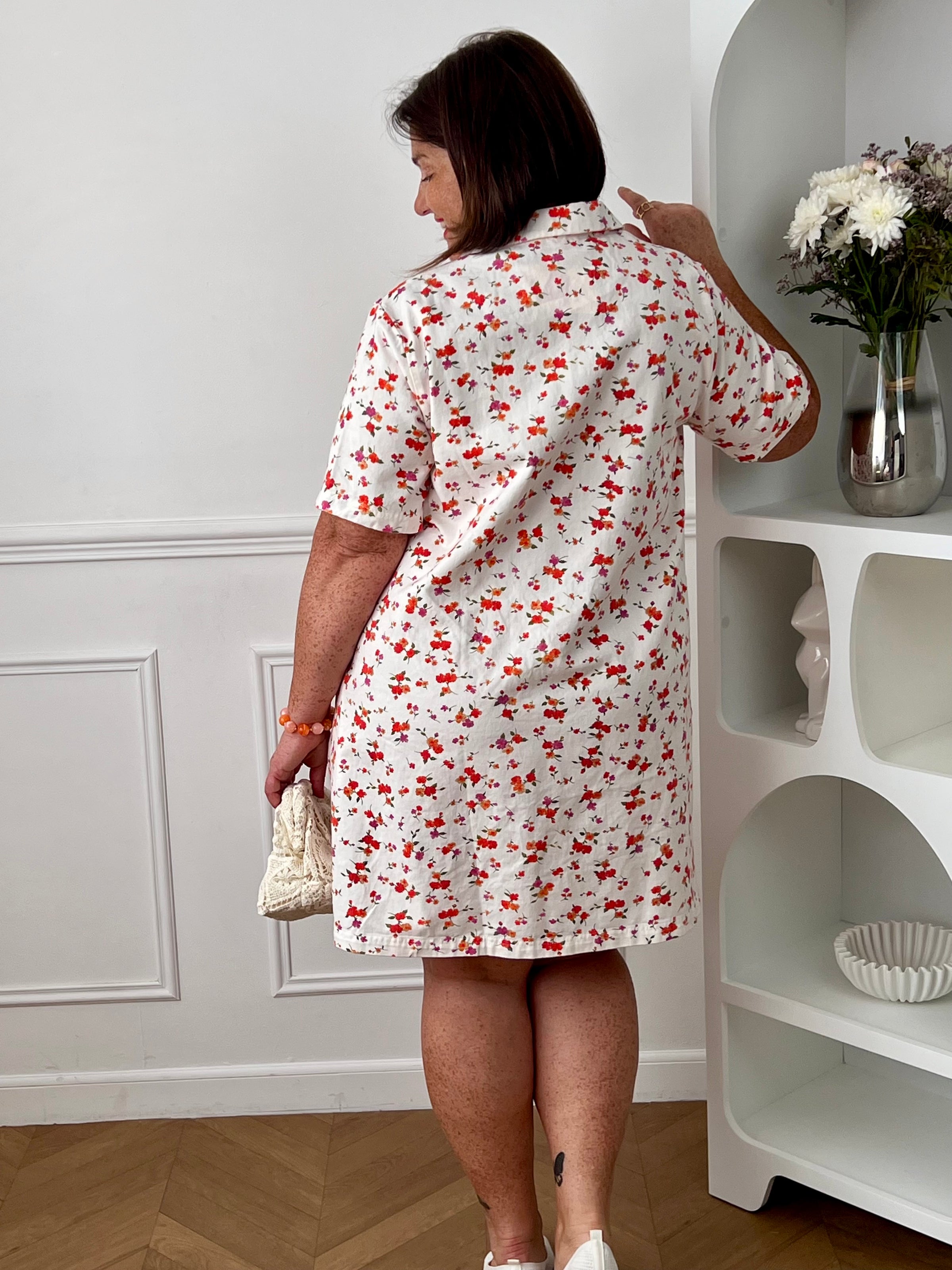 Robe à motifs femme grande taille, parfaite pour une allure féminine et colorée. Avec ses manches courtes, son col chemise ouvert en V et sa coupe ample, elle offre confort et élégance au quotidien. Dotée de deux poches poitrine et de deux poches latérales, elle allie style et praticité. Ses motifs fleuris aux tons écru, rouge, orange, vert et violet apportent une touche lumineuse et tendance, tandis que les boutons dorés aux poignets ajoutent une finition raffinée. Confectionnée en 100% coton, cette robe e