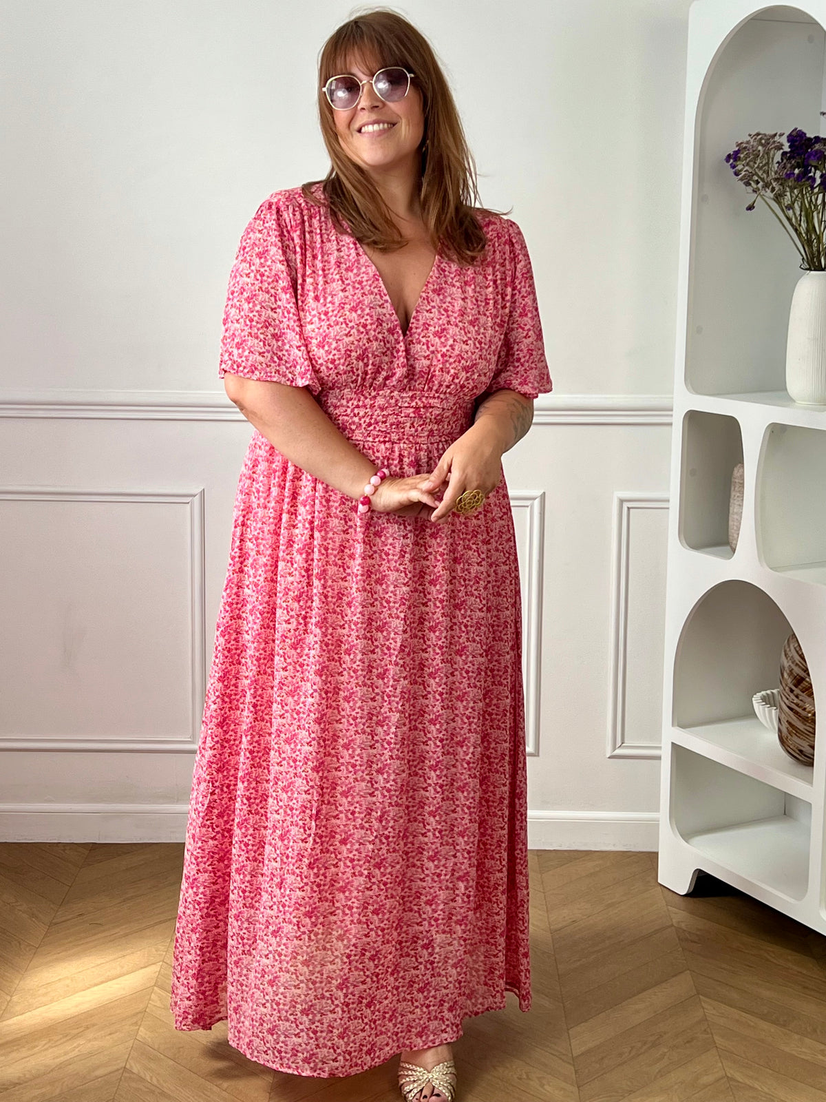 Apportez une touche de couleur et de féminité à votre dressing avec cette robe longue grande taille à motifs fleuris. Son col V et ses manches courtes lui confèrent une allure élégante et légère, tandis que sa taille élastiquée au dos assure un confort optimal et une silhouette harmonieuse. Doublée sur le corps pour plus d’aisance, elle reste légèrement transparente au niveau des manches pour un effet aérien.