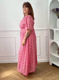 Apportez une touche de couleur et de féminité à votre dressing avec cette robe longue grande taille à motifs fleuris. Son col V et ses manches courtes lui confèrent une allure élégante et légère, tandis que sa taille élastiquée au dos assure un confort optimal et une silhouette harmonieuse. Doublée sur le corps pour plus d’aisance, elle reste légèrement transparente au niveau des manches pour un effet aérien.