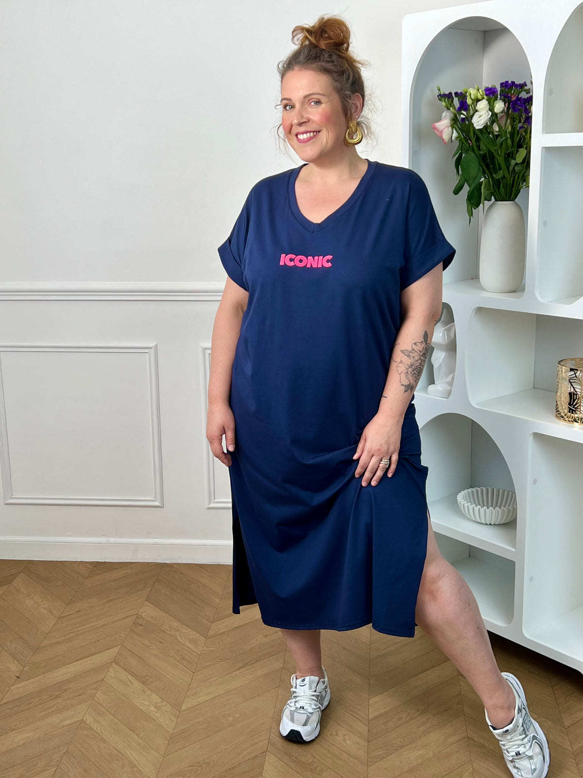 Robe longue bleue grande taille, parfaite pour un look confortable et tendance. Avec sa coupe droite, ses manches courtes et son col V, elle offre une silhouette fluide et agréable à porter. Ses inscriptions à l’avant et au dos apportent une touche moderne et originale. Fendue sur les côtés au bas de la robe, elle assure plus d’aisance et de mouvement. Disponible en bleu marine avec détails rose et orange, cette robe est idéale pour un style décontracté et féminin.
