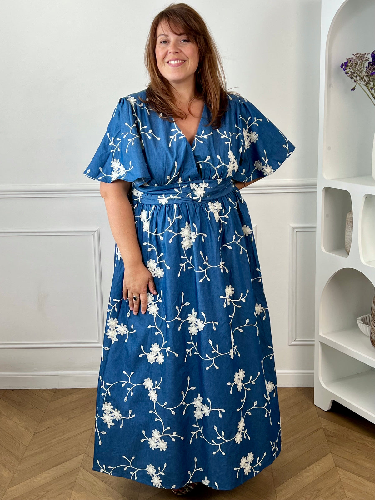 Craquez pour cette robe longue en coton grande taille femme, parfaite pour une allure élégante et confortable. Dotée d'un col V, de manches courtes et d'une taille élastiquée au dos, elle met en valeur la silhouette. Ses délicats motifs fleurs brodés dans des tons bleu marine et écru apportent une touche raffinée, idéale pour la belle saison.