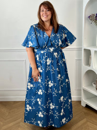 Craquez pour cette robe longue en coton grande taille femme, parfaite pour une allure élégante et confortable. Dotée d'un col V, de manches courtes et d'une taille élastiquée au dos, elle met en valeur la silhouette. Ses délicats motifs fleurs brodés dans des tons bleu marine et écru apportent une touche raffinée, idéale pour la belle saison.