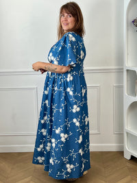 Craquez pour cette robe longue en coton grande taille femme, parfaite pour une allure élégante et confortable. Dotée d'un col V, de manches courtes et d'une taille élastiquée au dos, elle met en valeur la silhouette. Ses délicats motifs fleurs brodés dans des tons bleu marine et écru apportent une touche raffinée, idéale pour la belle saison.