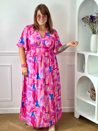 Laissez-vous séduire par cette robe longue grande taille au style féminin et coloré. Son col V et ses manches courtes apportent une touche d’élégance décontractée, tandis que sa taille élastiquée au dos assure un confort optimal et une belle mise en valeur de la silhouette. Sur un fond écru lumineux, ses motifs aux nuances rose fuchsia, jaune, bleu et violet apportent fraîcheur et originalité, faisant de cette robe la pièce idéale pour la saison.
