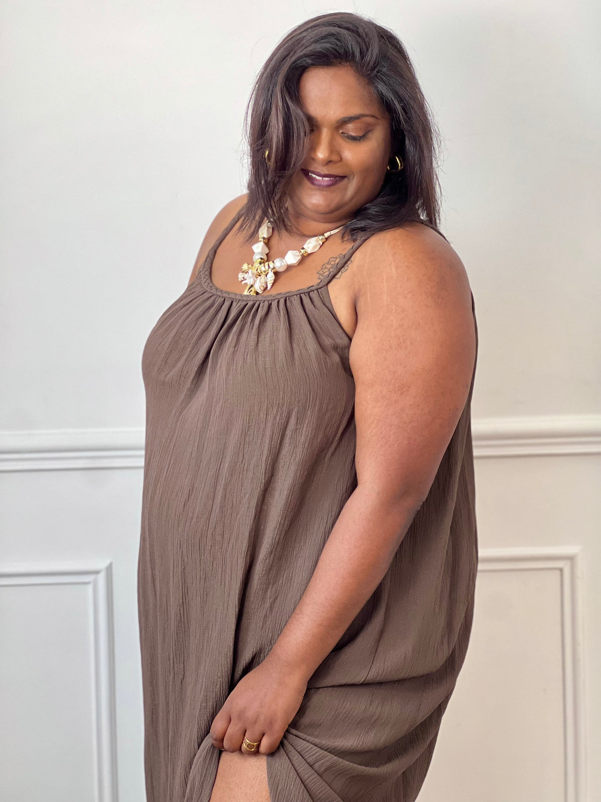 Robe longue marron femme grande taille, à la coupe ample et confortable. Dotée d’un col rond, de bretelles tressées non réglables et d’un élastique au dos pour un meilleur maintien. Ses fentes sur les côtés apportent fluidité et aisance, tandis que le fil lurex doré ajoute une touche lumineuse et élégante. Une robe idéale pour un look chic et décontracté.