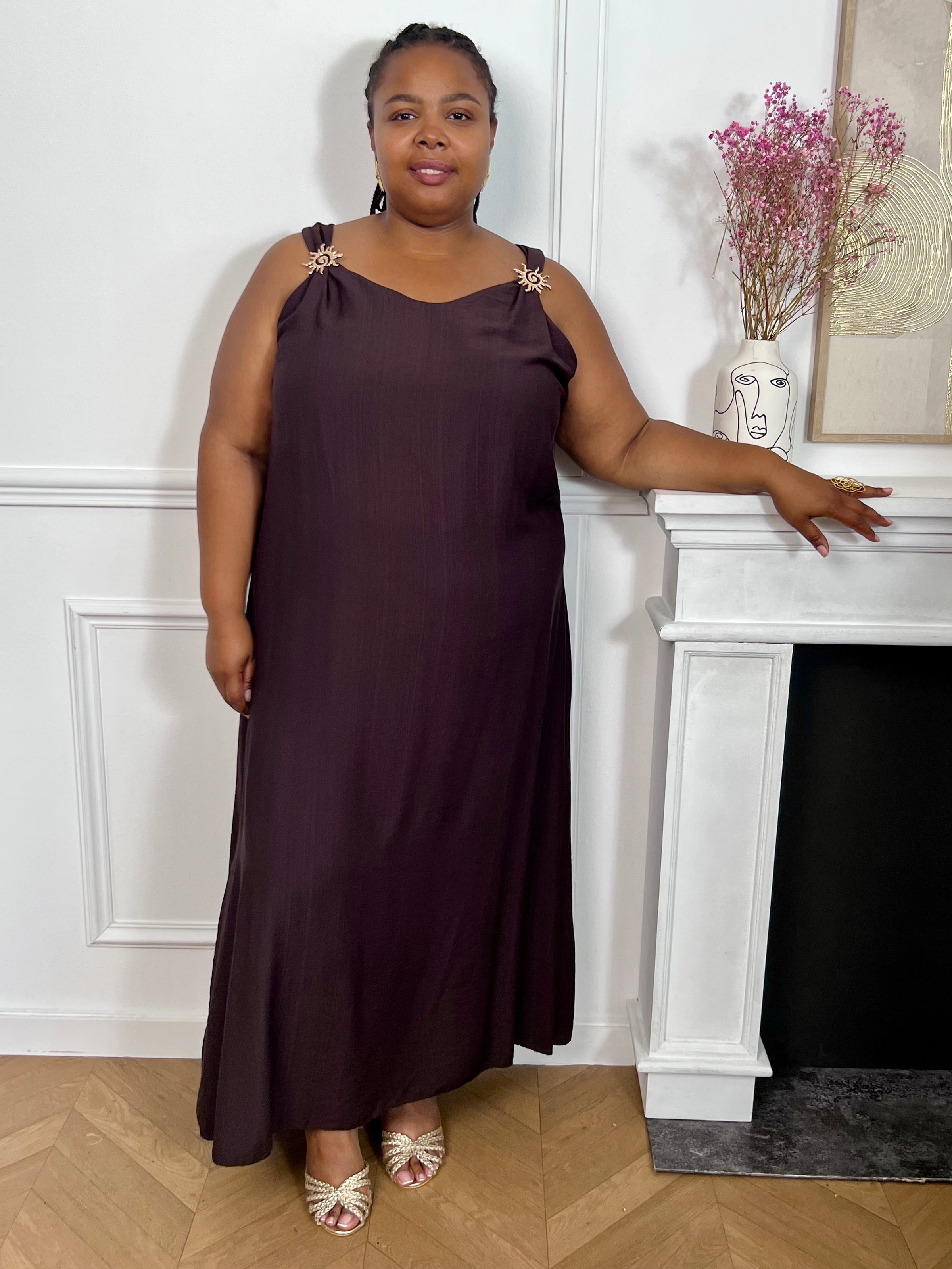 Adoptez cette robe grande taille à bretelles, élégante et facile à porter. Son col rond est sublimé par de jolies broches amovibles en forme de soleils dorés qui apportent une touche originale et raffinée. Sa couleur marron foncé en fait une pièce idéale pour un look chic en toute simplicité.