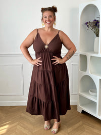Apportez une touche d'élégance à votre garde-robe avec cette robe longue à bretelles femme. Son col V met délicatement la silhouette en valeur, tandis que les bretelles réglables et l'élastique au dos assurent un ajustement confortable et personnalisé. La broche dorée amovible en forme de soleil apporte une finition raffinée et originale, idéale pour sublimer cette robe marron foncé. Une pièce chic et intemporelle, parfaite pour vos journées d'été comme pour vos occasions spéciales.