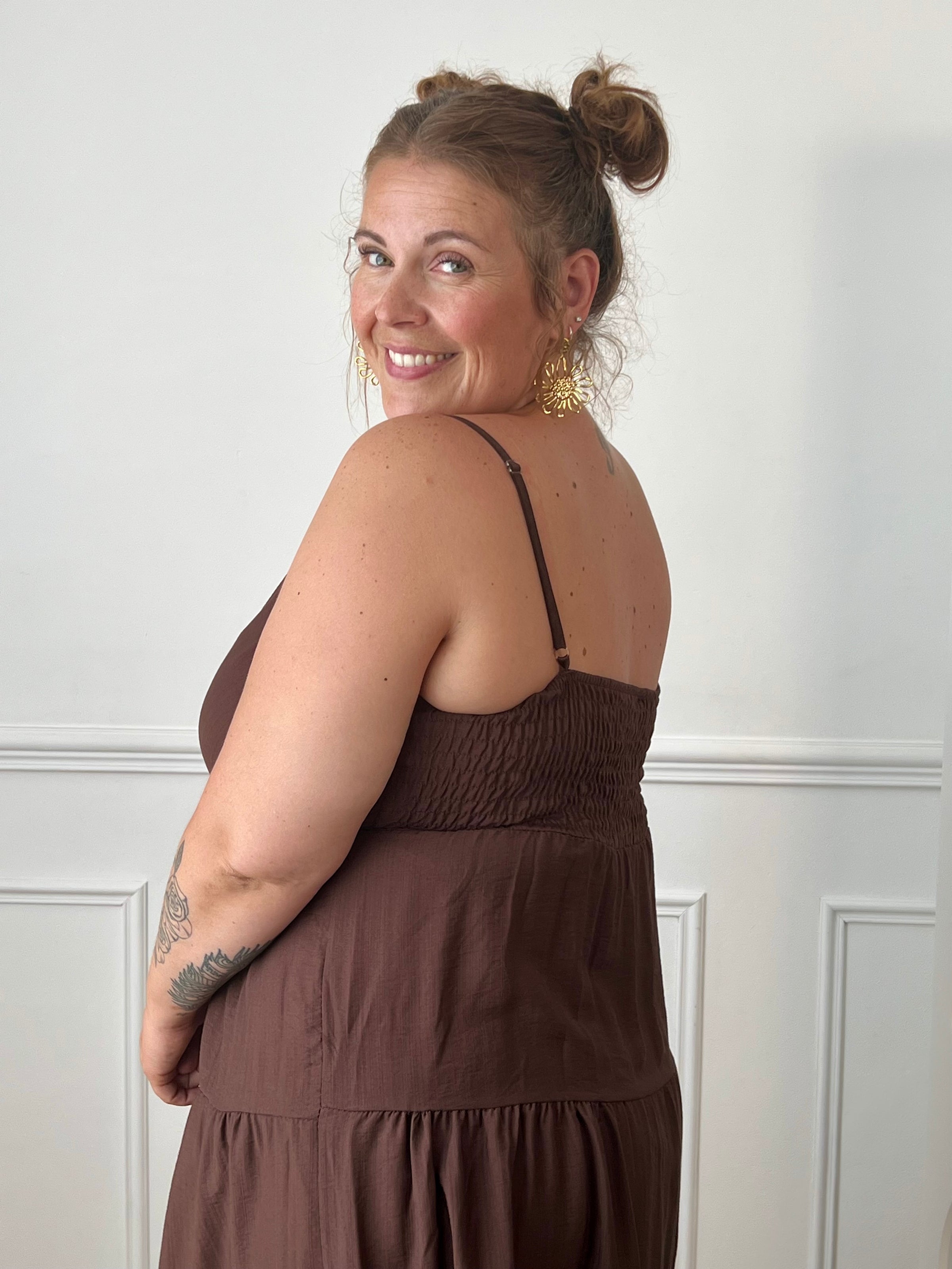 Apportez une touche d'élégance à votre garde-robe avec cette robe longue à bretelles femme. Son col V met délicatement la silhouette en valeur, tandis que les bretelles réglables et l'élastique au dos assurent un ajustement confortable et personnalisé. La broche dorée amovible en forme de soleil apporte une finition raffinée et originale, idéale pour sublimer cette robe marron foncé. Une pièce chic et intemporelle, parfaite pour vos journées d'été comme pour vos occasions spéciales.