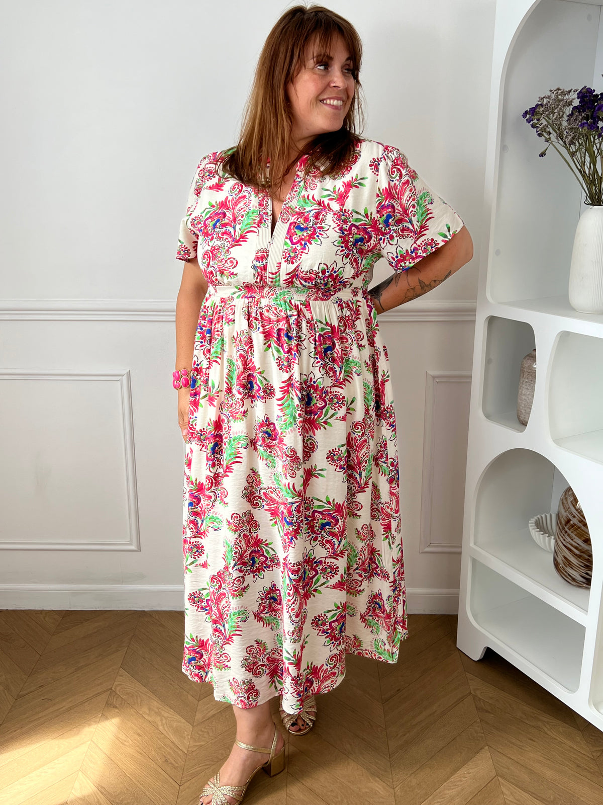 Laissez-vous séduire par cette robe longue écrue grande taille au charme bohème et féminin. Ses motifs colorés aux nuances de rose, vert, bleu et violet apportent une touche de fraîcheur et d’originalité à la silhouette. Dotée de manches courtes et d’un col V élégant, elle offre un confort optimal grâce à sa taille élastiquée au dos. Doublée au niveau de la jupe et sur le devant du haut, cette robe fluide est idéale pour un look à la fois chic, léger et confortable.