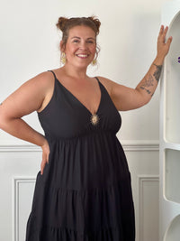 Apportez une touche d'élégance à votre garde-robe avec cette robe longue à bretelles femme. Son col V met délicatement la silhouette en valeur, tandis que les bretelles réglables et l'élastique au dos assurent un ajustement confortable et personnalisé. La broche dorée amovible en forme de soleil apporte une finition raffinée et originale, idéale pour sublimer cette robe noire. Une pièce chic et intemporelle, parfaite pour vos journées d'été comme pour vos occasions spéciales.