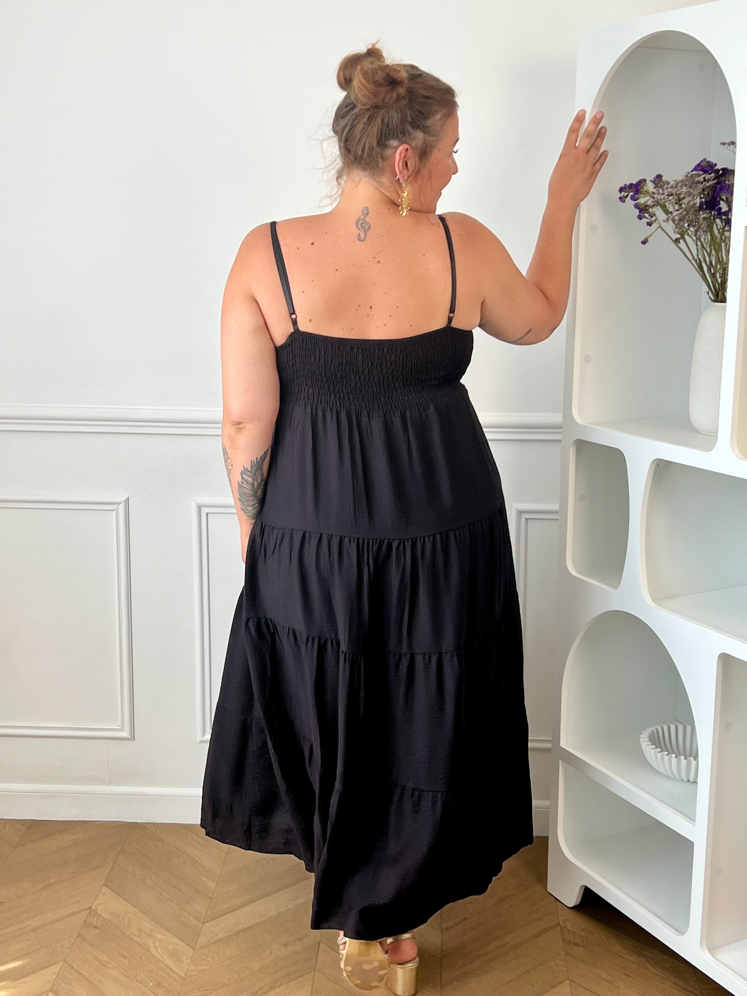 Apportez une touche d'élégance à votre garde-robe avec cette robe longue à bretelles femme. Son col V met délicatement la silhouette en valeur, tandis que les bretelles réglables et l'élastique au dos assurent un ajustement confortable et personnalisé. La broche dorée amovible en forme de soleil apporte une finition raffinée et originale, idéale pour sublimer cette robe noire. Une pièce chic et intemporelle, parfaite pour vos journées d'été comme pour vos occasions spéciales.