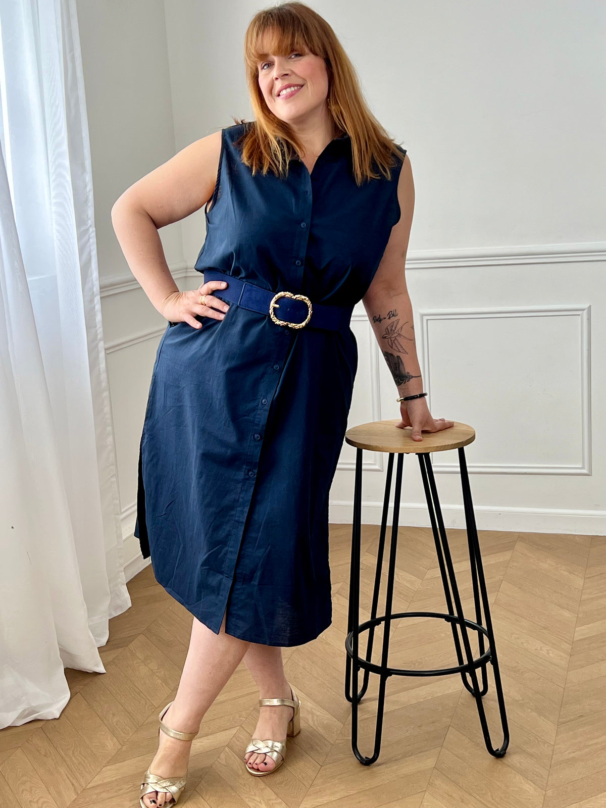 Adoptez cette robe en coton grande taille, à la fois confortable et structurée. Dotée d’un col chemise et de manches courtes avec revers, elle se ferme par des boutons. Sa ceinture amovible avec passants permet de marquer la taille. En noir, c’est une pièce intemporelle facile à porter au quotidien.