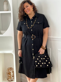 Adoptez cette robe en coton grande taille, à la fois confortable et structurée. Dotée d’un col chemise et de manches courtes avec revers, elle se ferme par des boutons. Sa ceinture amovible avec passants permet de marquer la taille. En noir, c’est une pièce intemporelle facile à porter au quotidien.