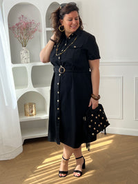 Adoptez cette robe en coton grande taille, à la fois confortable et structurée. Dotée d’un col chemise et de manches courtes avec revers, elle se ferme par des boutons. Sa ceinture amovible avec passants permet de marquer la taille. En noir, c’est une pièce intemporelle facile à porter au quotidien.