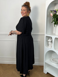 Sublimez votre silhouette avec cette robe longue grande taille au style élégant et féminin. Son col cache-cœur met délicatement le décolleté en valeur, tandis que l’élastique à la taille et aux poignets assure un confort optimal et un ajustement parfait. Le lien à nouer à la taille crée un joli effet portefeuille qui souligne la silhouette avec raffinement. Avec ses manches courtes et sa couleur noire intemporelle, cette robe est idéale pour toutes les occasions, du quotidien aux événements plus habillés.