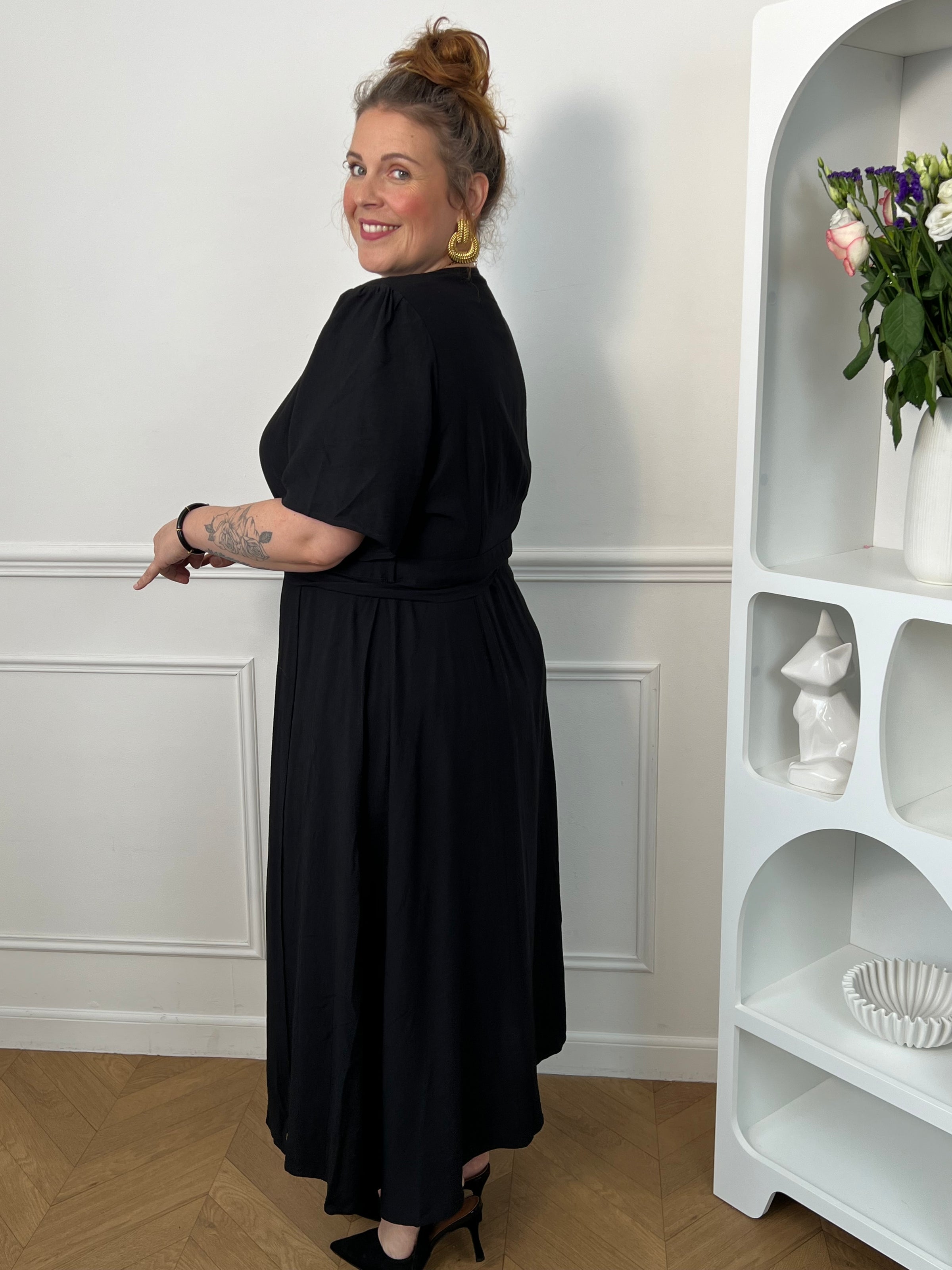 Sublimez votre silhouette avec cette robe longue grande taille au style élégant et féminin. Son col cache-cœur met délicatement le décolleté en valeur, tandis que l’élastique à la taille et aux poignets assure un confort optimal et un ajustement parfait. Le lien à nouer à la taille crée un joli effet portefeuille qui souligne la silhouette avec raffinement. Avec ses manches courtes et sa couleur noire intemporelle, cette robe est idéale pour toutes les occasions, du quotidien aux événements plus habillés.