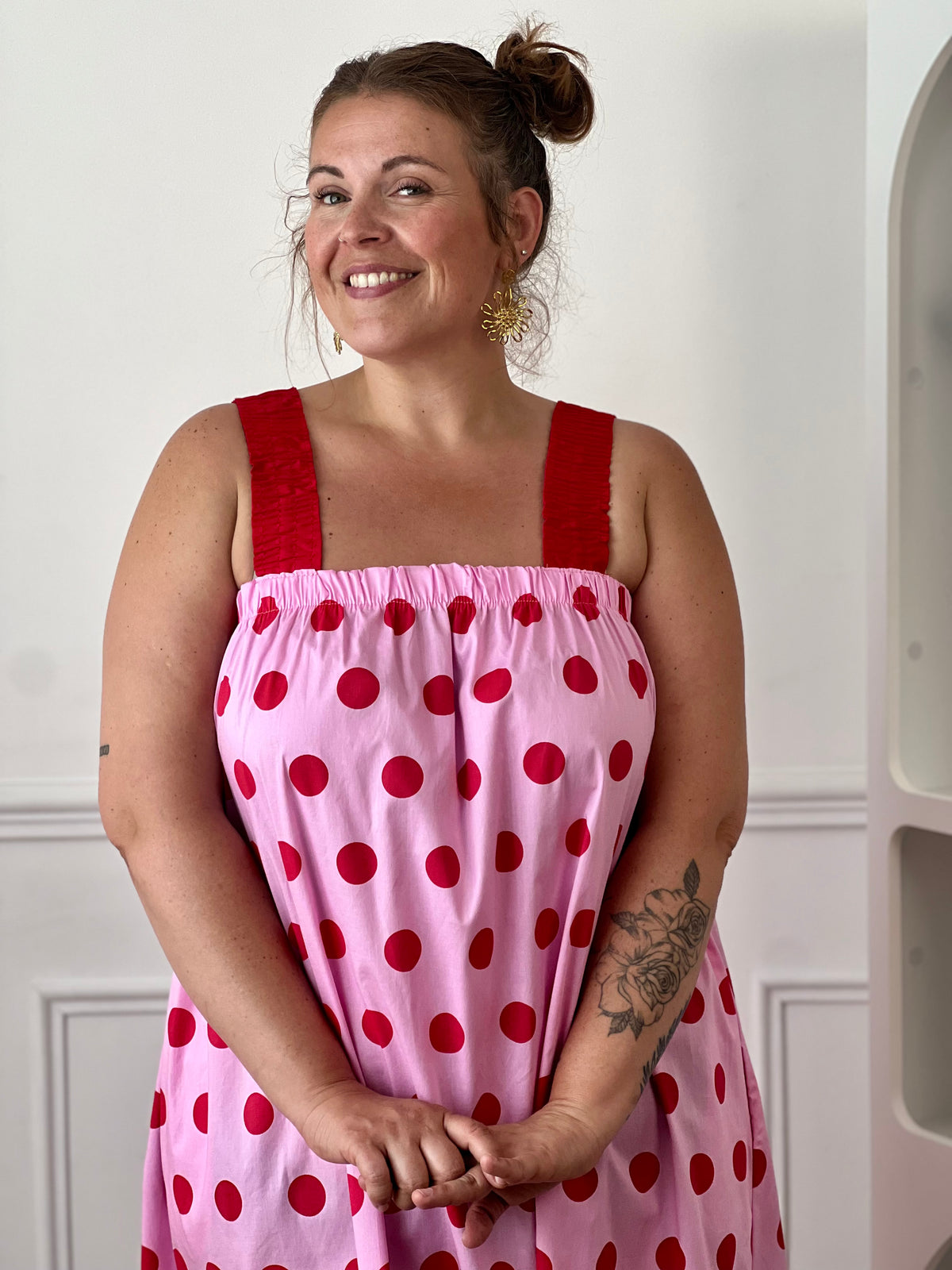Craquez pour cette robe longue grande taille au style doux et féminin. Son col carré élastiqué et ses bretelles élastiques assurent un confort optimal tout au long de la journée. Pratique grâce à ses deux poches latérales, elle séduit également par sa coupe droite qui offre une silhouette fluide et agréable à porter. Ses motifs pois rouges sur fond rose apportent une touche romantique et tendance, tandis que sa confection en 100% coton garantit légèreté et confort au quotidien.