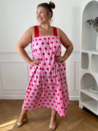 Craquez pour cette robe longue grande taille au style doux et féminin. Son col carré élastiqué et ses bretelles élastiques assurent un confort optimal tout au long de la journée. Pratique grâce à ses deux poches latérales, elle séduit également par sa coupe droite qui offre une silhouette fluide et agréable à porter. Ses motifs pois rouges sur fond rose apportent une touche romantique et tendance, tandis que sa confection en 100% coton garantit légèreté et confort au quotidien.