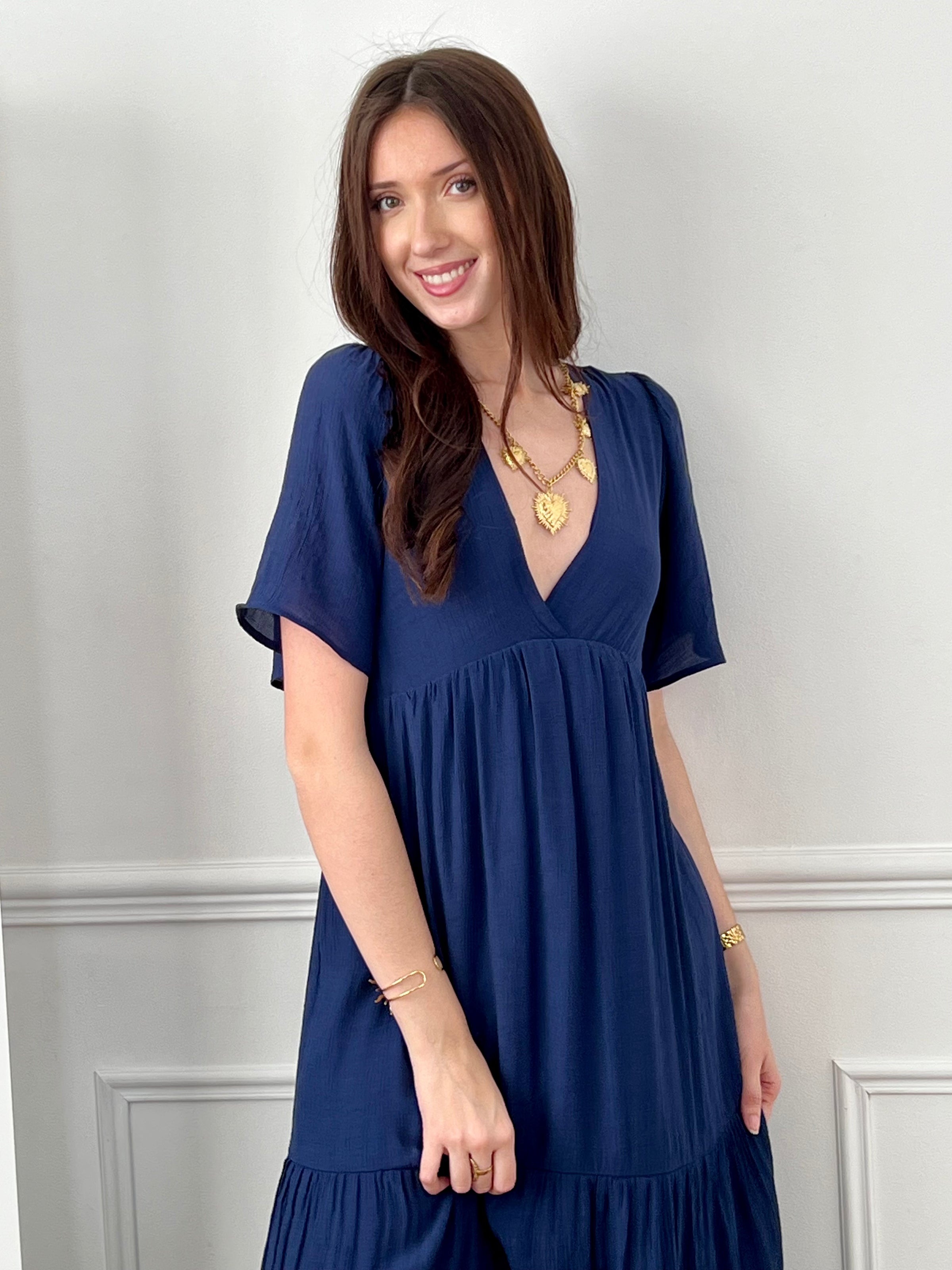 Craquez pour cette robe longue femme bleu marine, élégante et féminine. Dotée de manches courtes et d’un col V plongeant, elle met en valeur la silhouette. Son dos nu avec bouton et lien à nouer apporte une touche raffinée, tandis que sa taille élastique assure confort et maintien.