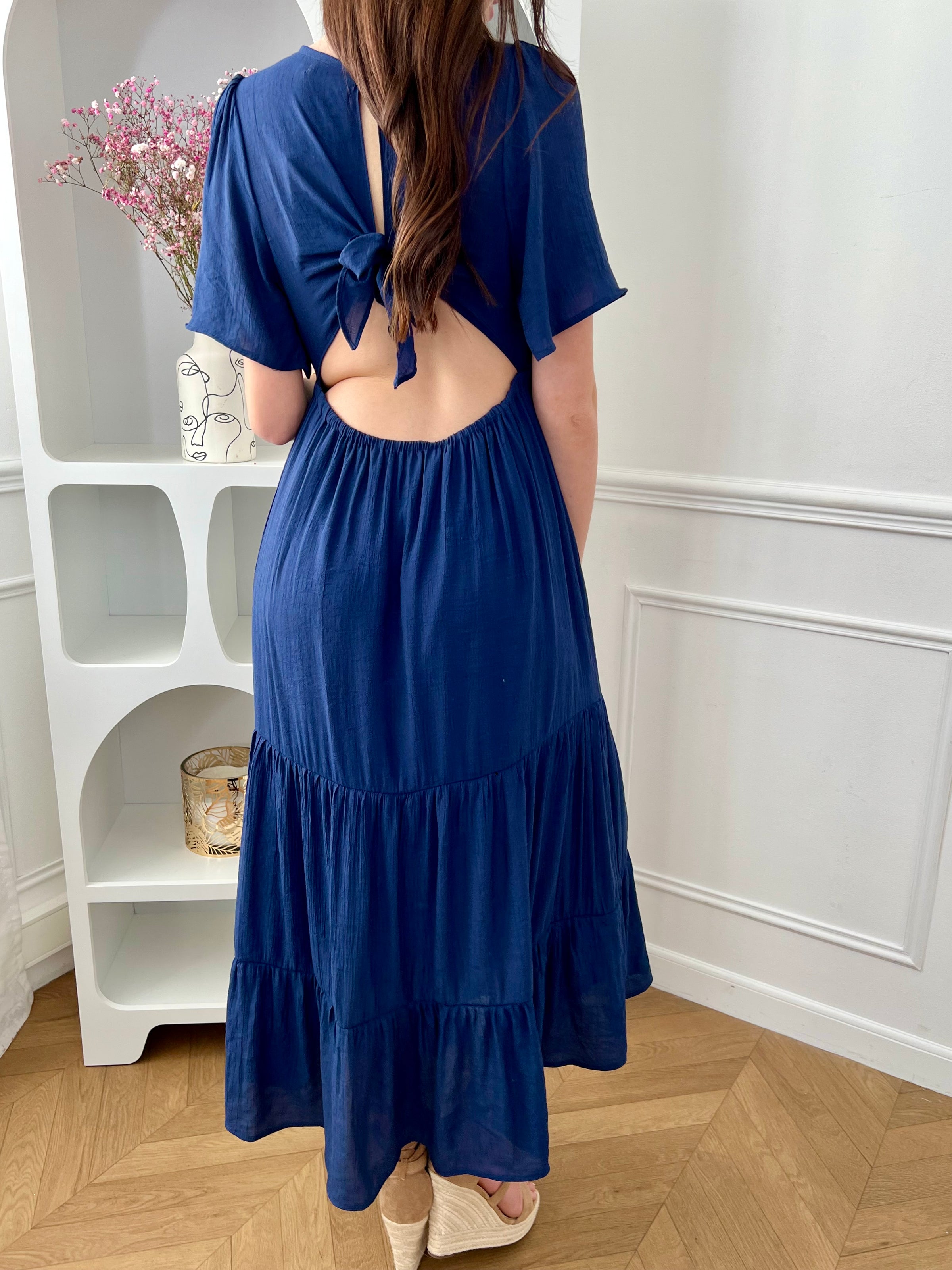 Craquez pour cette robe longue femme bleu marine, élégante et féminine. Dotée de manches courtes et d’un col V plongeant, elle met en valeur la silhouette. Son dos nu avec bouton et lien à nouer apporte une touche raffinée, tandis que sa taille élastique assure confort et maintien.