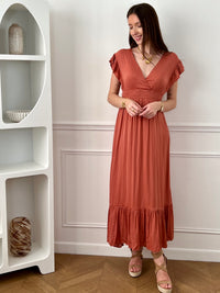 Craquez pour cette robe longue femme terracotta, élégante et féminine. Sans manches, elle se distingue par ses volants aux épaules et son col V plongeant qui sublime le décolleté. Son dos nu avec lien à nouer apporte une touche raffinée, tandis que sa taille élastique assure confort et maintien. Une pièce idéale pour un look chic et estival.