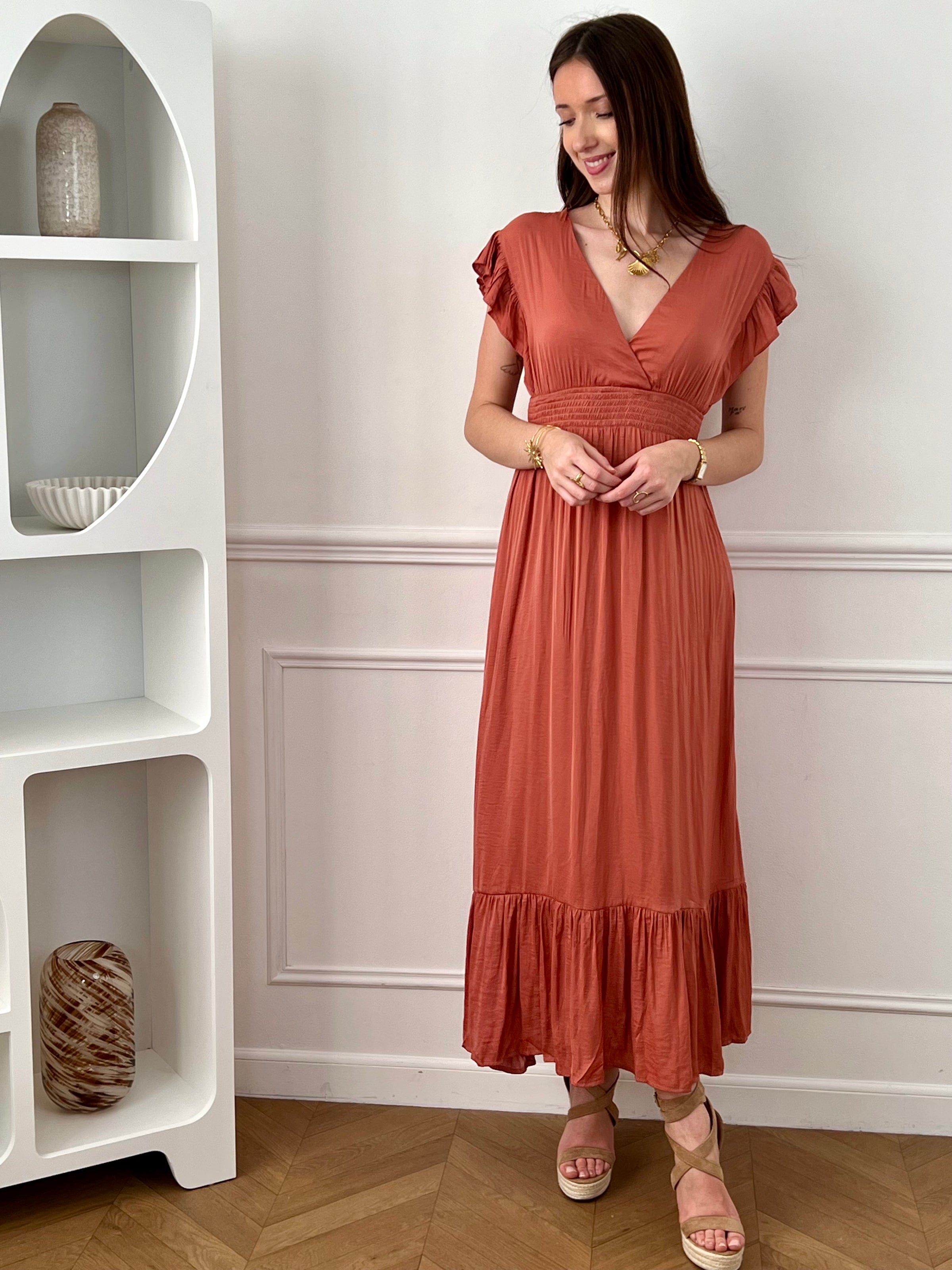 Craquez pour cette robe longue femme terracotta, élégante et féminine. Sans manches, elle se distingue par ses volants aux épaules et son col V plongeant qui sublime le décolleté. Son dos nu avec lien à nouer apporte une touche raffinée, tandis que sa taille élastique assure confort et maintien. Une pièce idéale pour un look chic et estival.