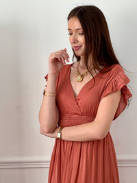 Craquez pour cette robe longue femme terracotta, élégante et féminine. Sans manches, elle se distingue par ses volants aux épaules et son col V plongeant qui sublime le décolleté. Son dos nu avec lien à nouer apporte une touche raffinée, tandis que sa taille élastique assure confort et maintien. Une pièce idéale pour un look chic et estival.
