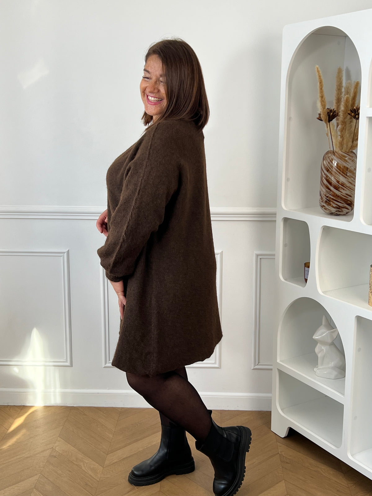 Robe pull marron grande taille vue de profil, portée avec des collants et des bottines noirs – Jessie | Loïcia