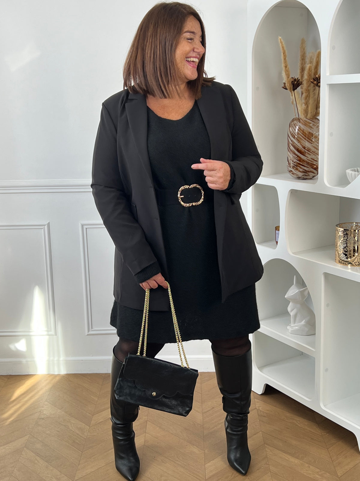 Robe pull noire ceinturée sous un blazer noir, portée avec des bottes hautes et un sac à chaîne dorée – Jessie | Loïcia