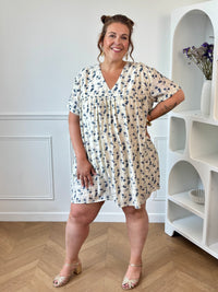 Adoptez cette robe short grande taille femme aux motifs fleuris bleu et beige, parfaite pour les beaux jours. Son col V, son dos nu fermé par un bouton, son élastique au dos et ses poches latérales offrent une coupe à la fois féminine et confortable. Une pièce pratique et tendance à porter en toute occasion.