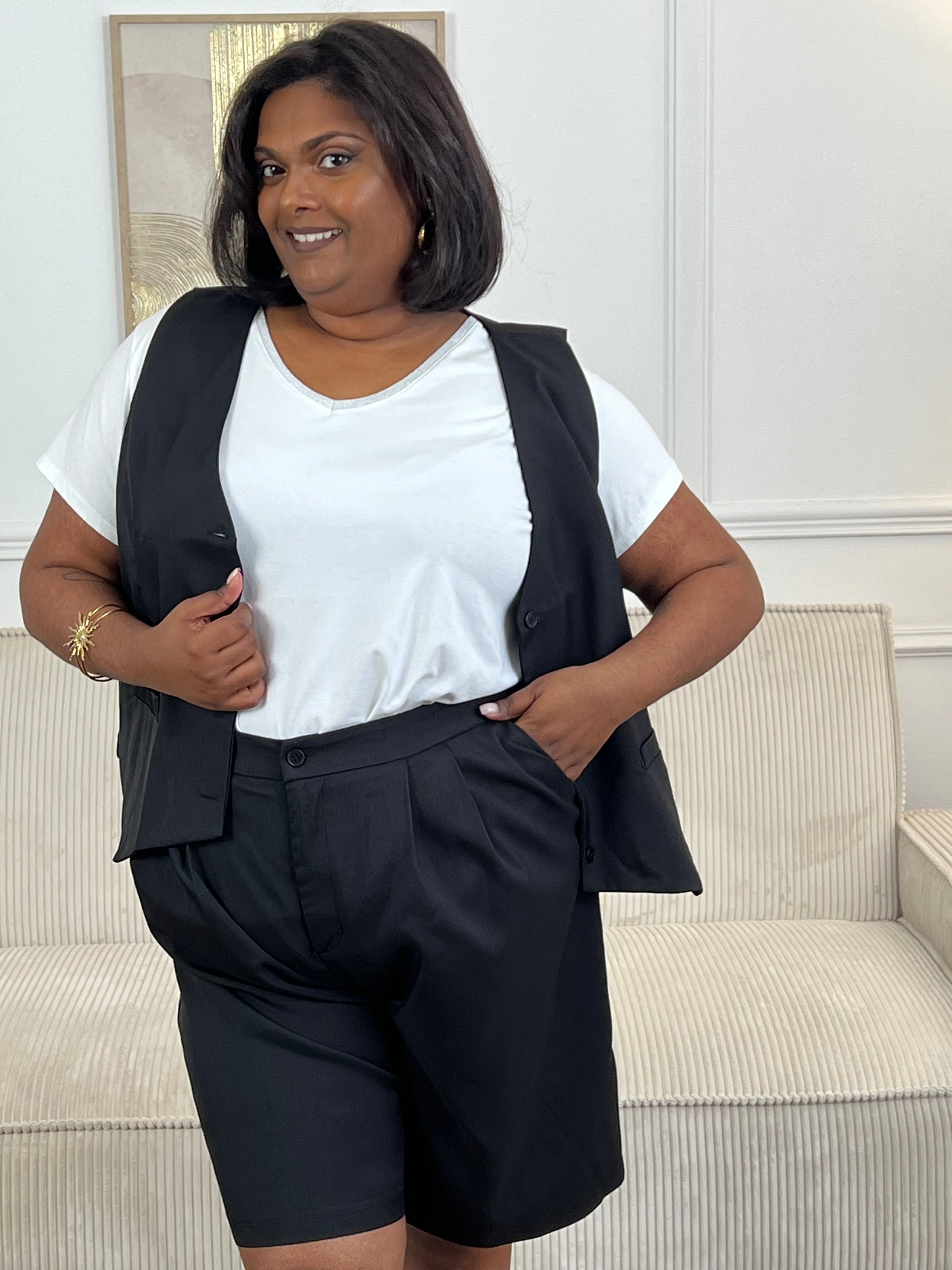 Adoptez ce short noir grande taille femme, à la fois confortable et facile à porter. Sa taille élastiquée assure un maintien optimal, complétée par une fermeture bouton et zip éclair. Sans passants, il offre une coupe épurée et dispose de deux poches à l’avant pratiques pour le quotidien.