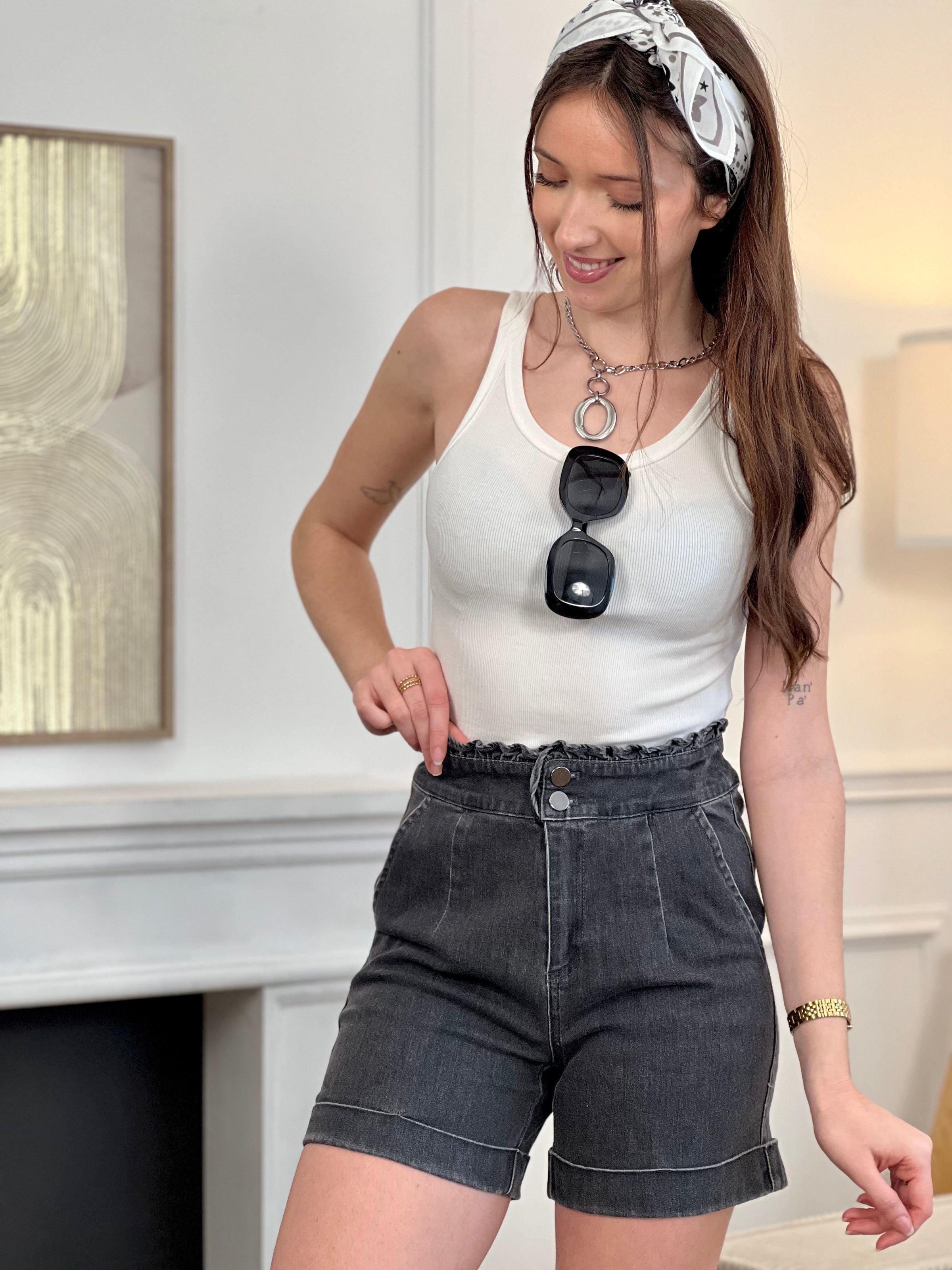 Adoptez ce short en coton femme taille haute, confortable et tendance. Doté de volants sur le haut pour une touche féminine, il se ferme par deux boutons et un zip. Ses deux poches à l’avant et ses revers en bas complètent son style. En gris foncé, il s’associe facilement à toutes vos tenues.