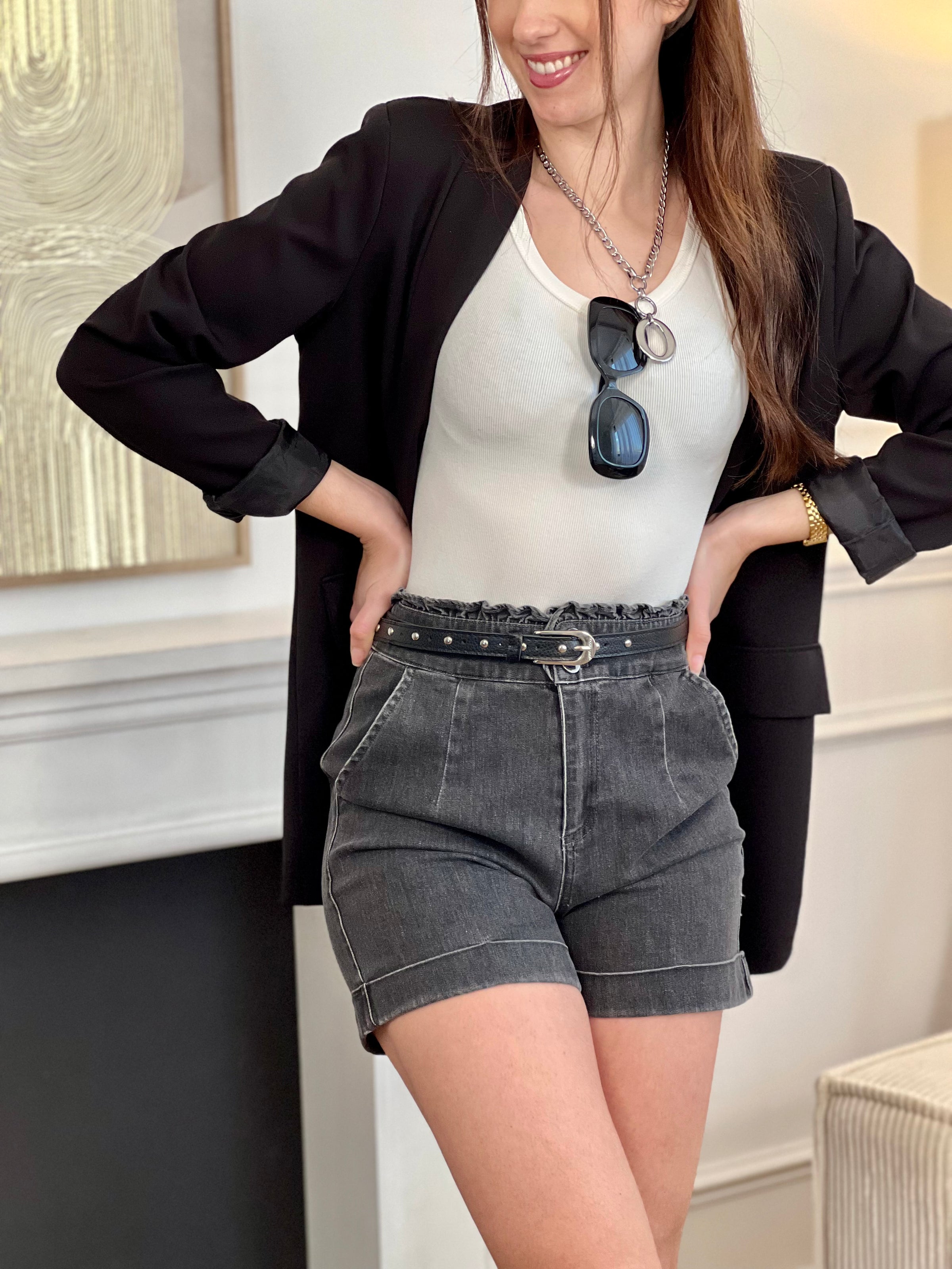 Adoptez ce short en coton femme taille haute, confortable et tendance. Doté de volants sur le haut pour une touche féminine, il se ferme par deux boutons et un zip. Ses deux poches à l’avant et ses revers en bas complètent son style. En gris foncé, il s’associe facilement à toutes vos tenues.