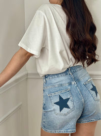 Short en jean femme, parfait pour un look casual et tendance. Doté d’une fermeture zippée, de deux poches à l’avant et de deux poches à l’arrière, il allie praticité et style. Ses motifs étoiles ornés de strass sur les poches arrière apportent une touche originale et lumineuse. Avec ses passants pour ceinture, ce short en jean bleu est un indispensable pour vos tenues estivales.