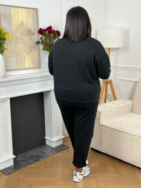 Pull grande taille noir à manches longues avec col rond, orné de l’inscription "Iconic club" en doré pour une touche féminine et raffinée.