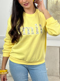 Sweat jaune confortable aux manches longues, parfait pour les journées fraîches. Son col rond classique offre une allure intemporelle, tandis que l'inscription "SMILE" brodée avec des motifs fleuris délicats ajoute une touche de personnalité et de douceur. Un basique polyvalent à porter seul ou en superposition, idéal pour exprimer votre style avec bienveillance.