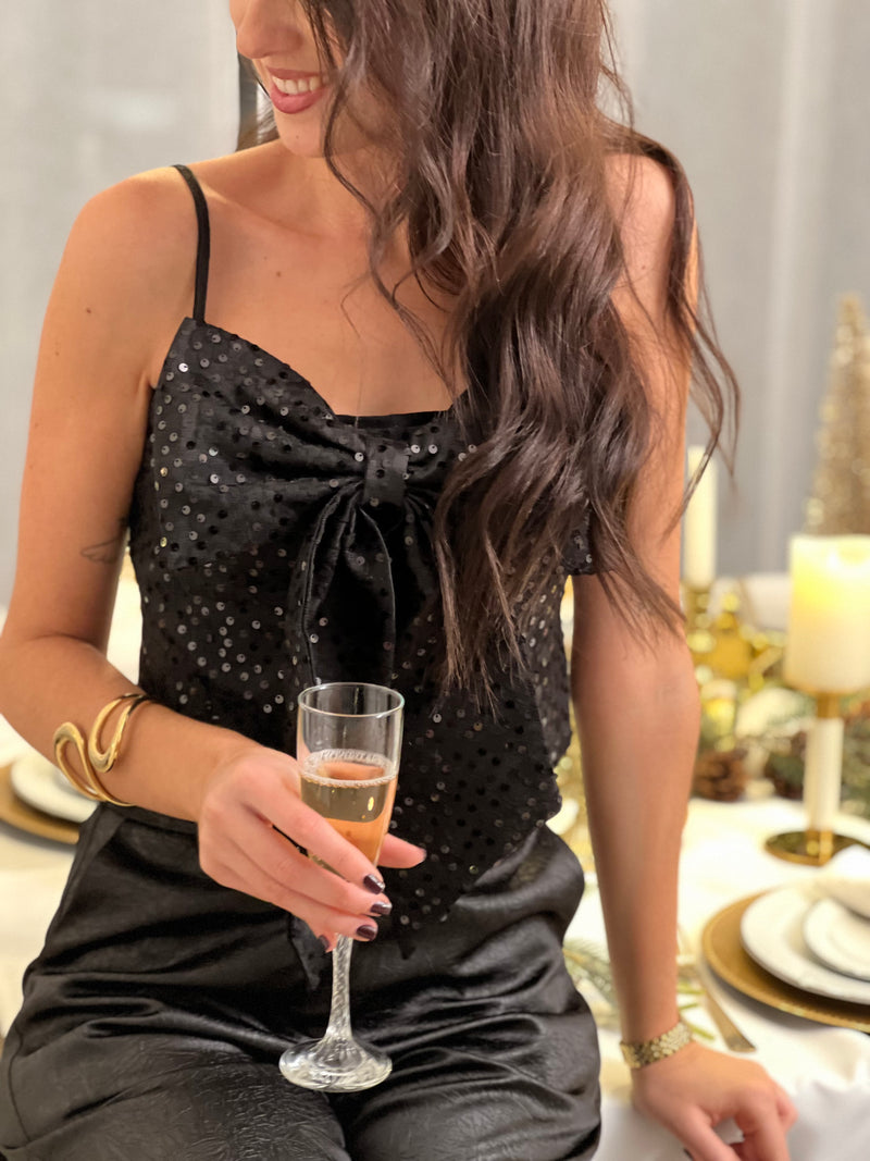 Le top bustier Neela allie style et confort avec ses bretelles réglables et son élégant nœud frontal. Paré de sequins et motifs noirs scintillants, ce bustier noir est votre allié pour des looks glamour et sophistiqués.