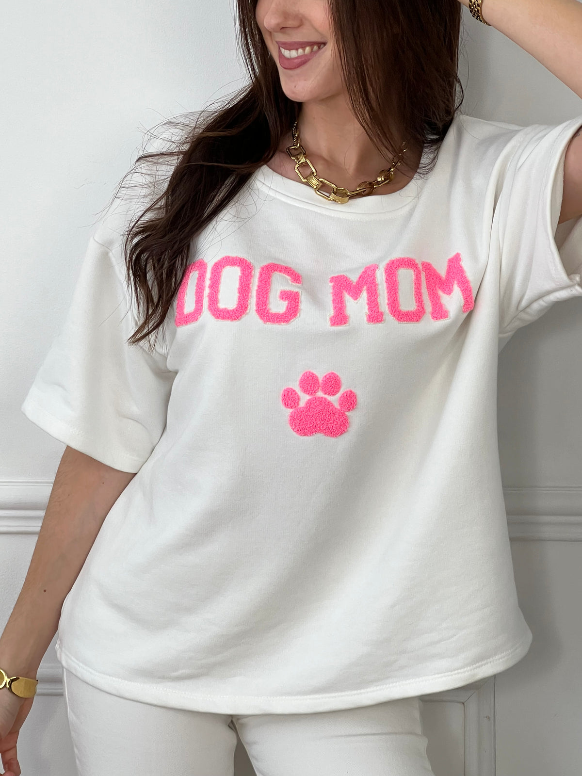 Craquez pour ce tee-shirt style sweat femme, confortable et tendance. Doté de manches courtes et d’un col rond, il est confectionné en 100 % coton pour un confort optimal. Son inscription “Dog mom” en rose et écru avec une patte de chien apporte une touche fun et originale.