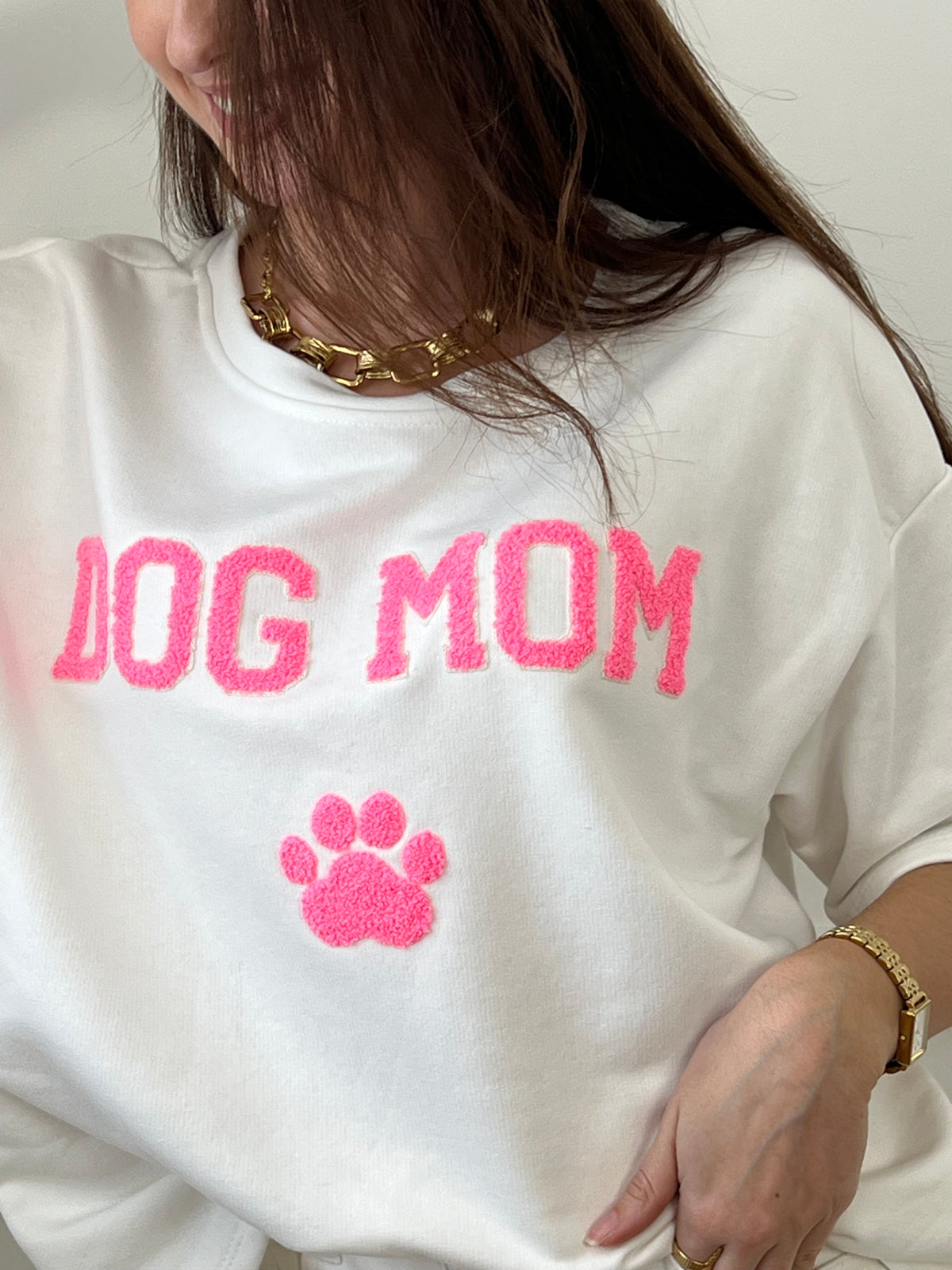 Craquez pour ce tee-shirt style sweat femme, confortable et tendance. Doté de manches courtes et d’un col rond, il est confectionné en 100 % coton pour un confort optimal. Son inscription “Dog mom” en rose et écru avec une patte de chien apporte une touche fun et originale.