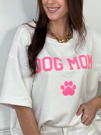 Craquez pour ce tee-shirt style sweat femme, confortable et tendance. Doté de manches courtes et d’un col rond, il est confectionné en 100 % coton pour un confort optimal. Son inscription “Dog mom” en rose et écru avec une patte de chien apporte une touche fun et originale.